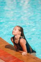 liten förtjusande flicka i utomhus- simning slå samman foto