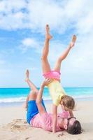 familj av far och sportig liten flicka har roligt på de strand foto