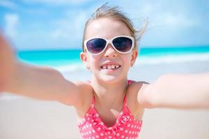 Lycklig liten flicka tar selfie på tropisk strand på exotisk ö foto