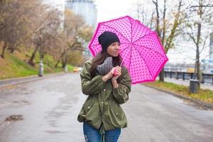 ung kvinna gående med paraply i höst regnig dag foto