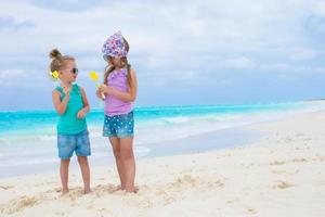 liten förtjusande flickor med ägg på vit tropisk strand foto