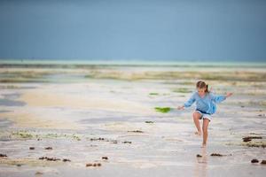 bedårande glad liten flicka ha kul på grunt vatten på strandsemester foto