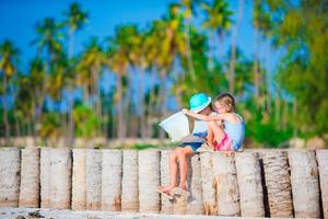 bedårande små flickor med karta över ön på stranden foto