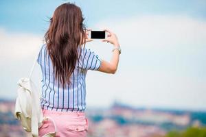 ung caucasian kvinna framställning Foto av europeisk gammal stad förbi mobil telefon från de observation plats