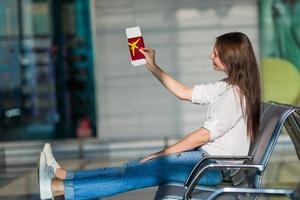 Lycklig ung kvinna med luft biljett och pass på flygplats väntar för ombordstigning foto
