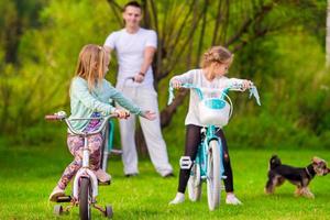 familj av ung far och liten barn cykling på sommar värma dag foto