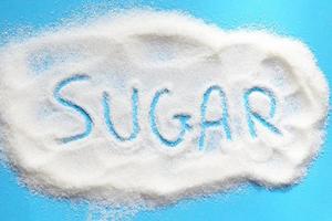 vit socker för mat och sötsaker efterrätt godis högen av ljuv socker kristallin granulerad - socker på blå bakgrund foto