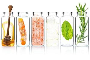 de glas flaska av hemlagad hud vård och kropp scrubs med naturlig Ingredienser aloe vera ,himalaya salt , pepparmynta ,rosmarin ,gurkmeja och honung isolera på vit bakgrund. foto