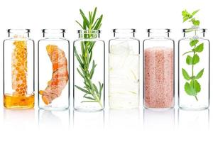 de glas flaska av hemlagad hud vård och kropp scrubs med naturlig Ingredienser aloe vera ,himalaya salt , pepparmynta ,rosmarin ,gurkmeja och honung isolera på vit bakgrund. foto