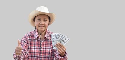 isolerat äldre asiatisk kvinna innehar oss dollar Bank anteckningar i hand med skön leende på henne ansikte lyckligt med klippning stigar. foto