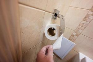 stänga upp av person hand använder sig av toalett papper. foto