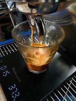 kaffe maskin fyllning en kopp med expresso. transparent råna i automatiserad kaffebryggare maskin. dryck dryck för frukost foto
