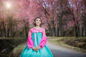 hanbok, de traditionell koreanska klänning och skön asiatisk flicka med sakura foto