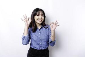 upphetsad asiatisk kvinna ger ett ok hand gest isolerat förbi en vit bakgrund foto