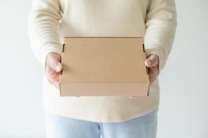 kvinna händer bärande brun kartong låda. begrepp av använder sig av återvinna papper låda. foto