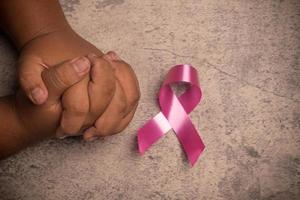 rosa band om på hand på grå bakgrund.bröst cancer behandling begrepp. foto