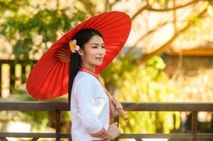 asiatisk kvinna bär typisk thai klänning med röd paraply., thai kostym foto