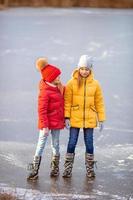 förtjusande flickor skridskoåkning på is rink utomhus i vinter- snö dag foto