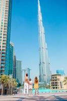 Lycklig familj gående i dubai med burj khalifa skyskrapa i de bakgrund. foto