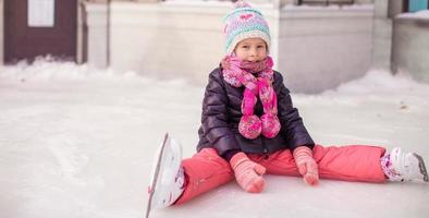 liten förtjusande flicka Sammanträde på is efter de falla foto