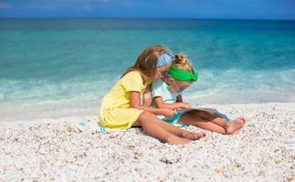 liten söt flickor med stor Karta på tropisk strand semester foto