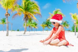förtjusande liten flicka i santa hatt under jul strand semester foto