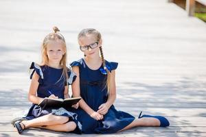 förtjusande liten skola flickor med anteckningar och pennor utomhus. tillbaka till skola. foto