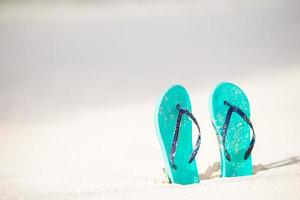 sommar mynta flip flops med solglasögon på vit strand foto