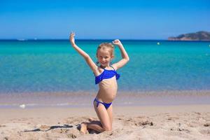 förtjusande liten flicka ha roligt på tropisk vit sandig strand foto