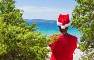 ung man i santa hatt under strand semester foto