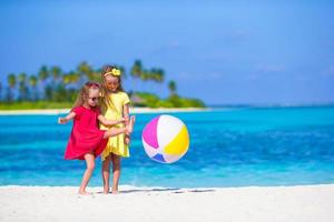 liten förtjusande flickor spelar på strand med boll foto