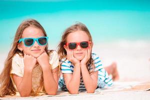 liten Lycklig rolig flickor ha en massa av roligt på tropisk strand spelar tillsammans. solig dag med regn i de hav foto