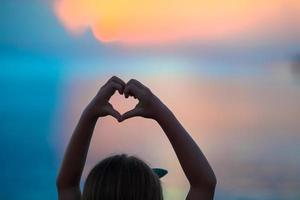 silhuett av hjärta tillverkad förbi barn hand på solnedgång foto