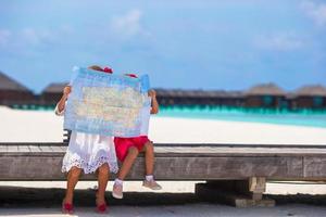 bedårande små flickor med karta över ön på stranden foto