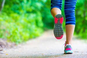 närbild på sko av idrottare löpare kvinna fötter löpning på väg foto