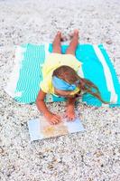 förtjusande liten flicka med stor Karta på strand semester foto