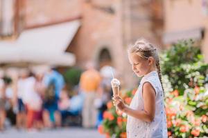 förtjusande liten flicka äter glass utomhus på sommar. foto