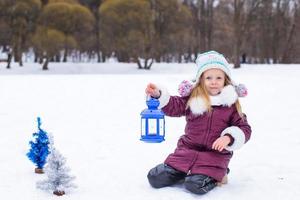 förtjusande liten flicka innehav jul lykta utomhus på skön vinter- snö dag foto
