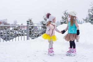 liten flickor skridskoåkning på is rink utomhus i vinter- snö dag foto