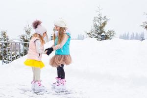 liten flickor skridskoåkning på is rink utomhus i vinter- snö dag foto