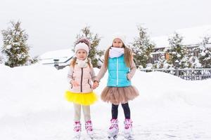 förtjusande liten flickor skridskoåkning på is rink utomhus i vinter- snö dag foto