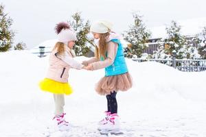 liten flickor skridskoåkning på is rink utomhus i vinter- snö dag foto