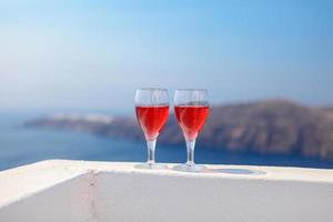 två glasögon av gott röd vin på solnedgång i grekland foto