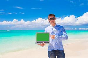 ung man med bärbar dator under strand semester foto