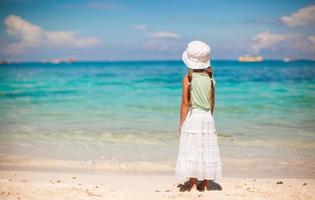 förtjusande liten flicka som går på den tropiska vita stranden foto