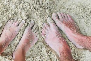 närbild fötter av en ung par på vit sand strand foto