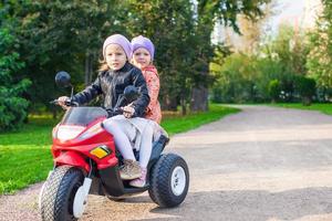 förtjusande liten flickor ridning på barn motorcykel i de grön parkera foto
