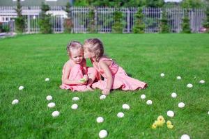 två förtjusande liten flickor har roligt med påsk ägg på grön gräs foto