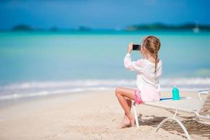 liten flicka gör video eller foto med sin kamera sitter på solsängen