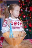liten flicka bakning pepparkaka småkakor för jul på kök foto